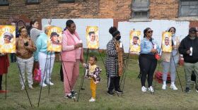 A line of people with the faces of Saturday's shooting victims on yellow posters.