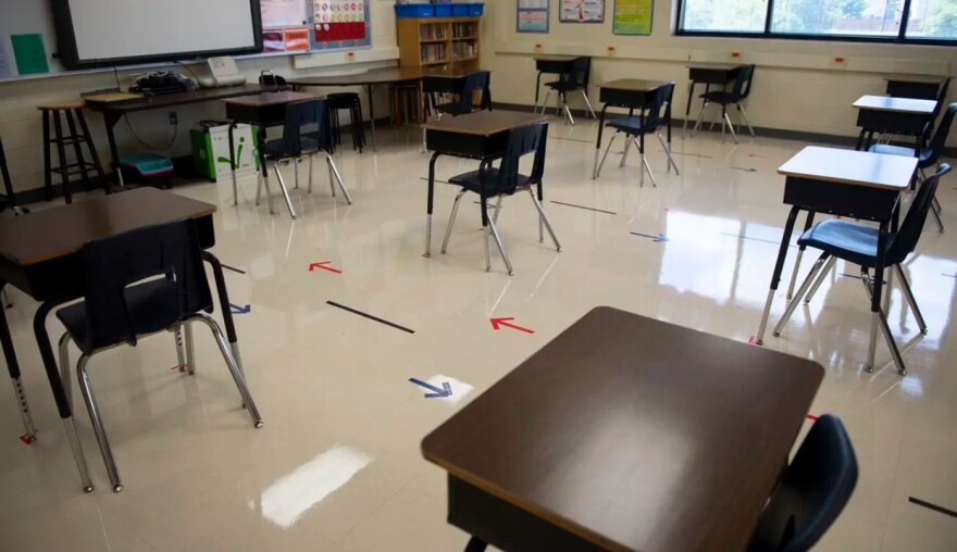 An empty classroom with arrows on the floor directing the flow of student traffic.