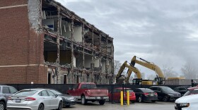 parking lot with two excavators in the background tearing down a brick building
