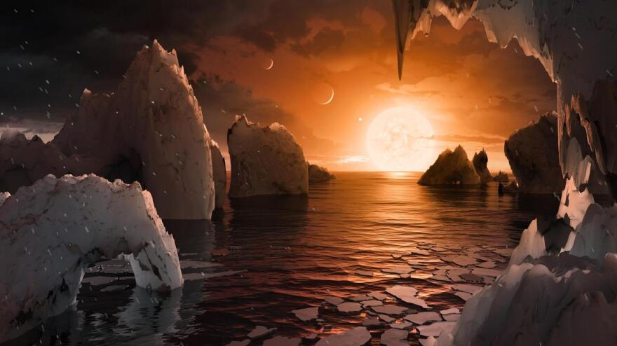 This artist's concept allows us to imagine what it would be like to stand on the surface of the exoplanet TRAPPIST-1f, located in the TRAPPIST-1 system in the constellation Aquarius. Because this planet is thought to be tidally locked to its star, meaning the same face of the planet is always pointed at the star, there would be a region called the terminator that perpetually divides day and night. If the night side is icy, the day side might give way to liquid water in the area where sufficient starlight hits the surface.