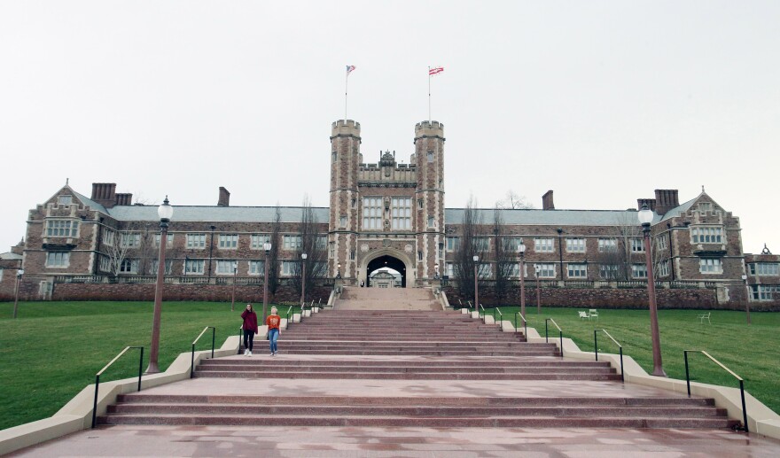 Two students walk down the long stairwell in front of Brookings Administration Building at Washington University in St. Louis in March. The university plans to furlough up to 1,300 employees by next week. 