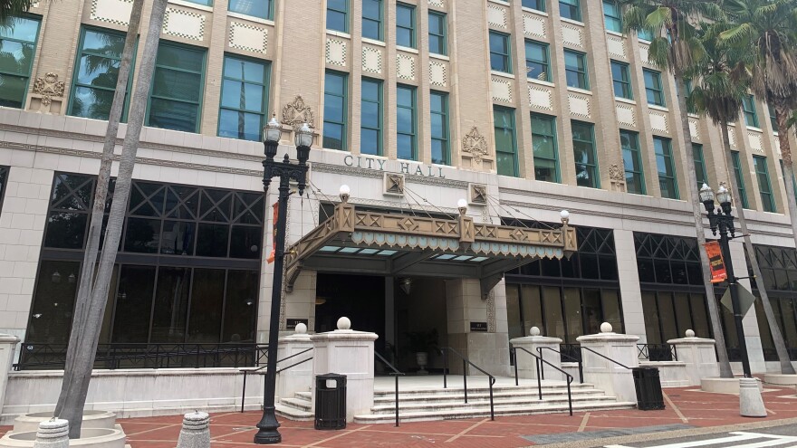 Outside of City Hall, large building with steps leading to the entrance, a couple of palm trees out in the front