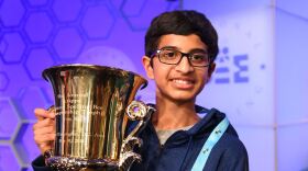 A picture of a boy with a spelling bee trophy