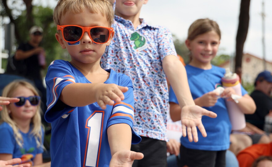 Brothers, Ezra, left, and Wesley Morris, right, gator chomp during the University of Florida Homecoming parade in Gainesville Friday, Oct. 9, 2026. (Taylin Huffman/WUFT News)
