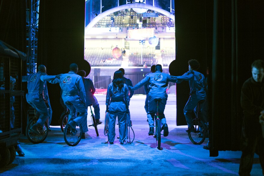 A team of unicyclists hold on to each other backstage. The King Charles Troupe has been playing basketball on unicycles since the '60s.