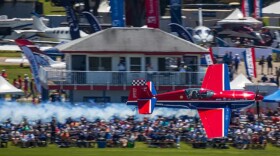 Red airplane flies over crowd 