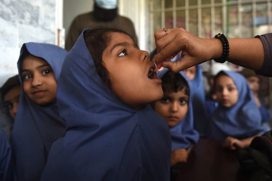 A health worker administers the oral polio vaccine to a girl as other children wait their turn at a school in Karachi, Pakistan, on February 28, 2022. In response to a rise in vaccine-derived polio cases , a form of the disease that is derived from the oral vaccine: Many countries are rolling out a new oral polio vaccine.