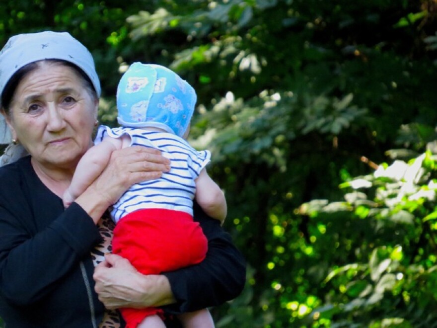 An Uzbek woman helps watch children who were playing during Eid celebration at park in Olivette.