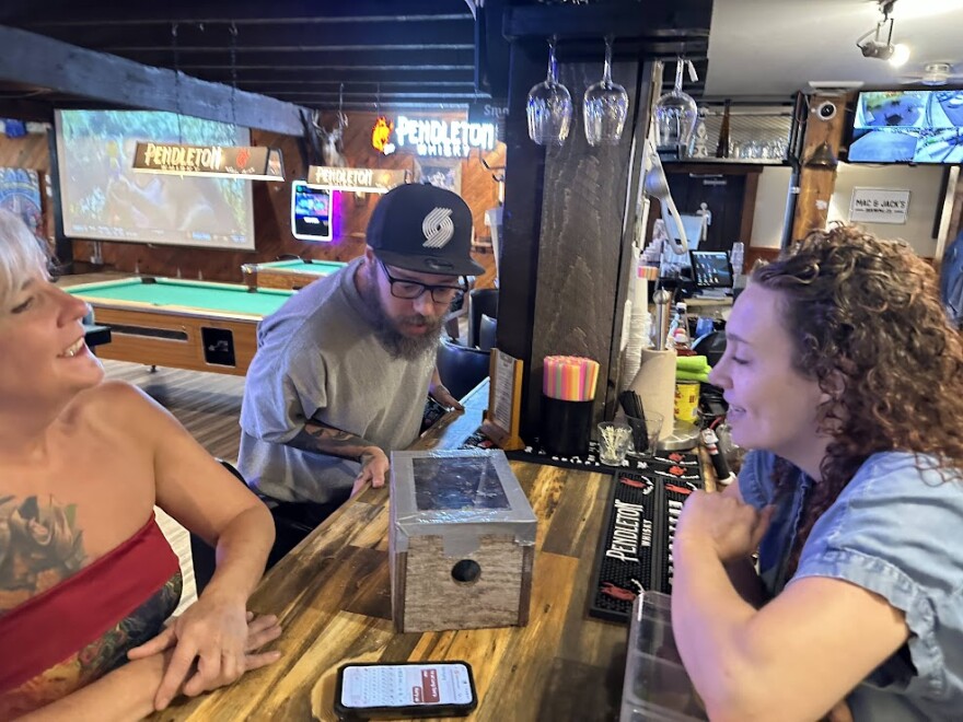 People in bar looking at box.