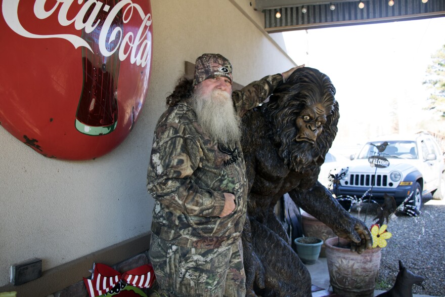 Charles Benton, who claims to have seen Bigfoot, stands with a statue of the creature in front of Janet's Treasure Chest in Honobia, Okla. 