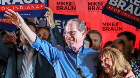Mike Braun, with one arm wrapped around his wife Maureen, waves to a crowd of supporters at his primary election night celebration on May 7, 2024.