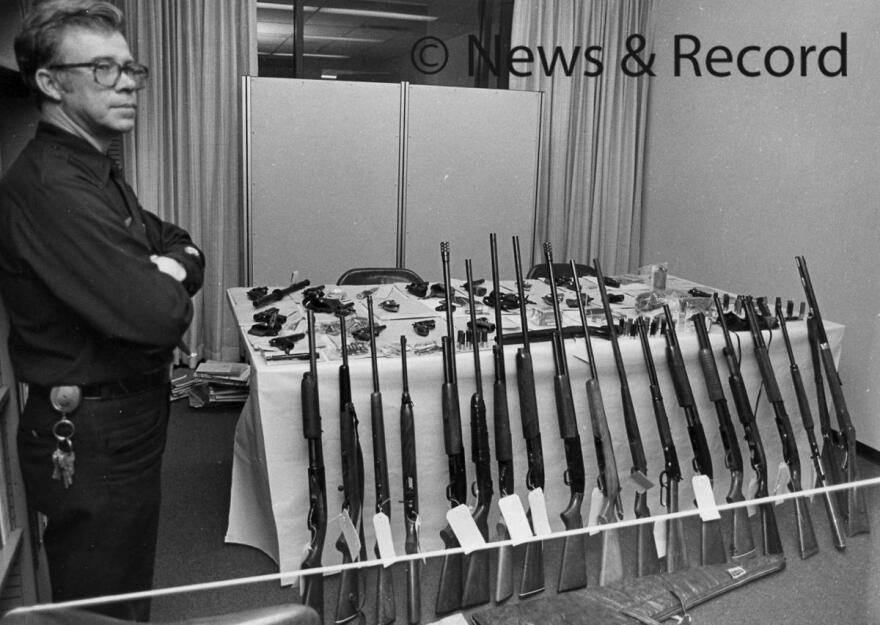 Greensboro Police Officer C.F. Brande keeps an eye on weapons confiscated from the Nazi-Klan shootout, on Nov. 14, 1979.