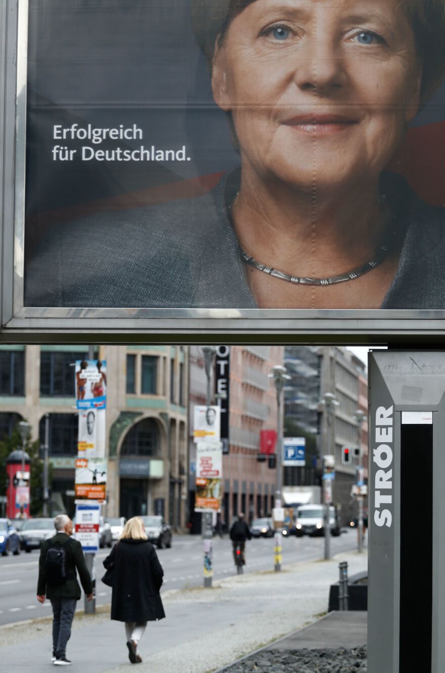 Pedestrians in Berlin walk past an election poster for Merkel. The message on the poster reads "Successful for Germany."