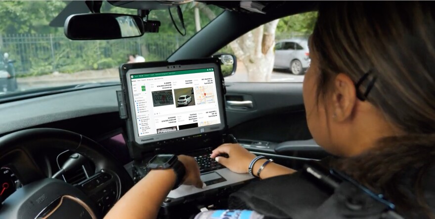 A female officer looking at a laptop in a car