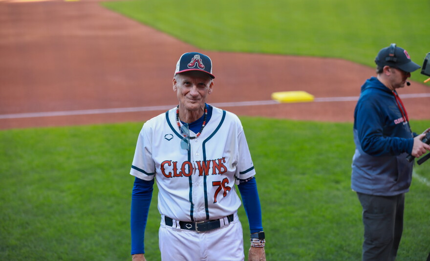 Older man dressed in Indianapolis Clowns uniform smiling for the camera on the field of Progressive Field.