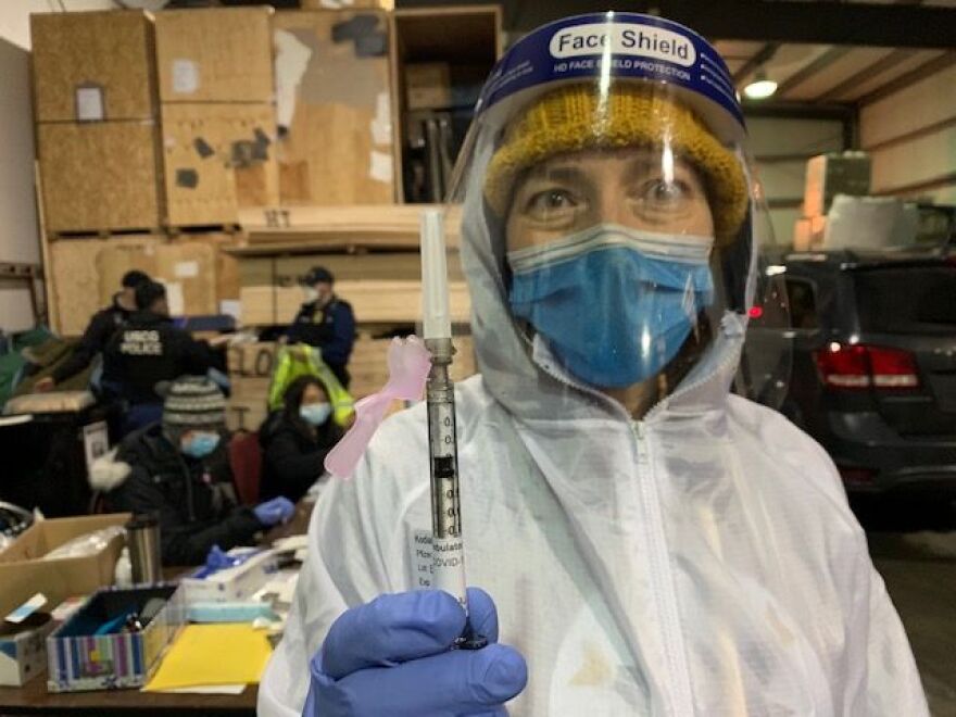 Dr. Shana Theobald holds up a dose of the COVID-19 vaccine.