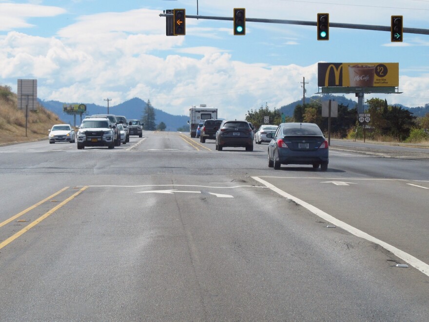 Cars drive through rutted pavement at an intersection