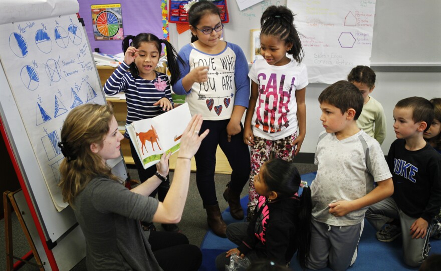 Teacher Elizabeth Carinder helps a group of her students present a book to their class.