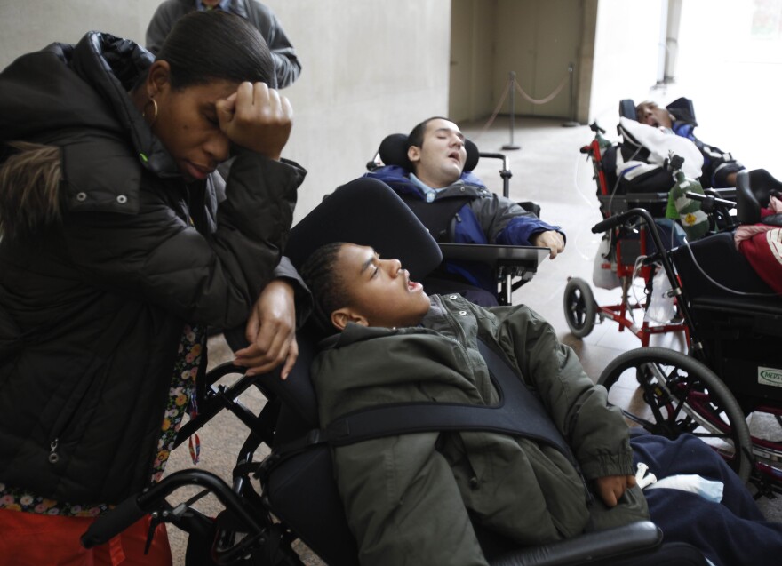 This Nov. 24, 2009 photo shows nurse assistant Yolette Coriolan resting her head on Jonathan Ramos' wheelchair during a field trip to the Metropolitan Museum of Art in New York. Ramos and the other children visiting the museum reside at Speciality Hospital in Terence Cardinal Cooke Health Care Center in New York.  To visitors, Specialty Hospital, home to 50 of the sickest, most vulnerable young people, can appear a deeply disturbing place. But for those who live and work here, Specialty represents all the joy and happiness and nurturing safety of home. (AP Photo/Seth Wenig)