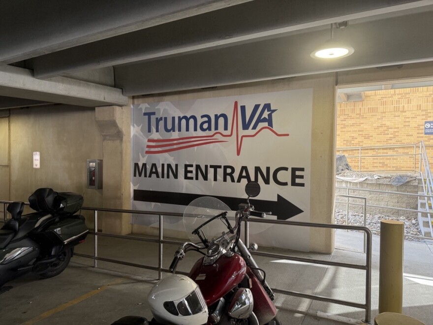 A sign inside the Truman VA parking garage reads "Truman VA Main Entrance" in large red and blue letters with an American flag background.