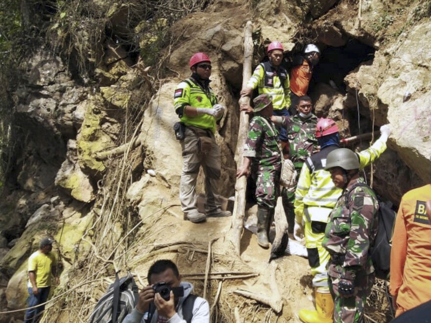 Rescuers stand at the entrance of a collapsed mine in Sulawesi, Indonesia, on Thursday. The shouting of trapped miners ceased on Saturday.