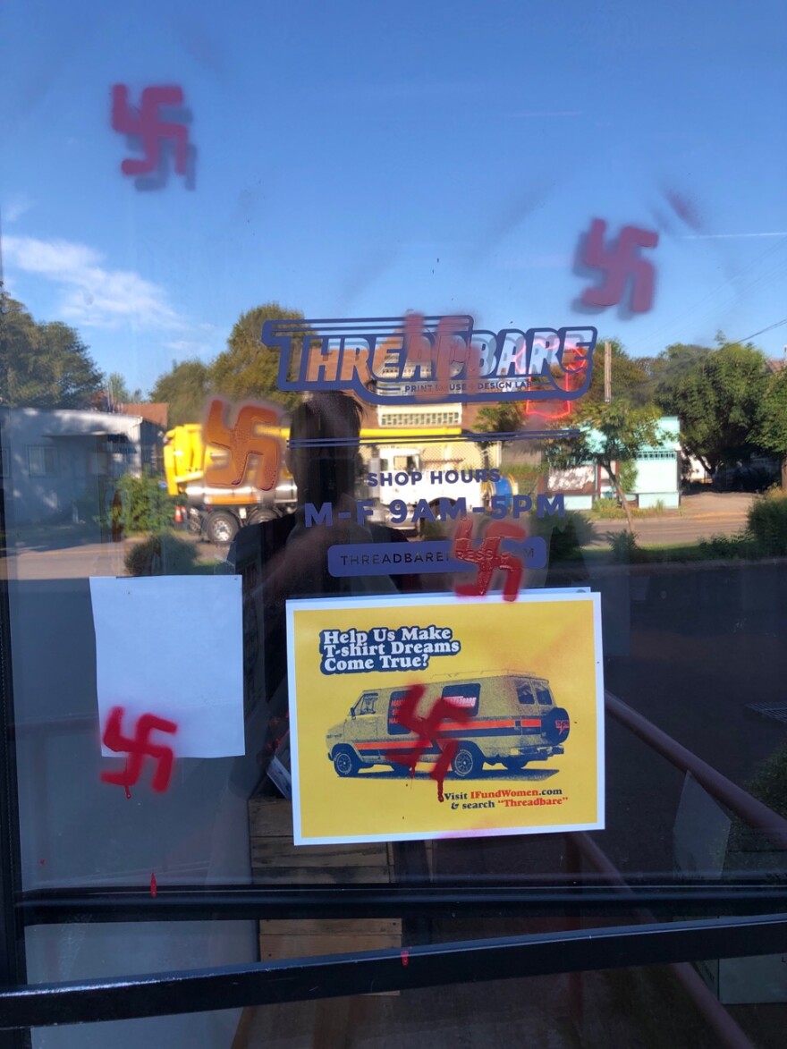 Photo shows swastikas painted on the front entrance of Threadbare Print House in downtown Eugene.