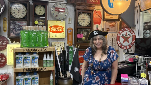 Cheryl Ring stands behind the counter at the Buccaneer Gift Shop in Fort Walton Beach, wearing a pirate hat and surrounded by vintage signs, clocks and souvenirs.