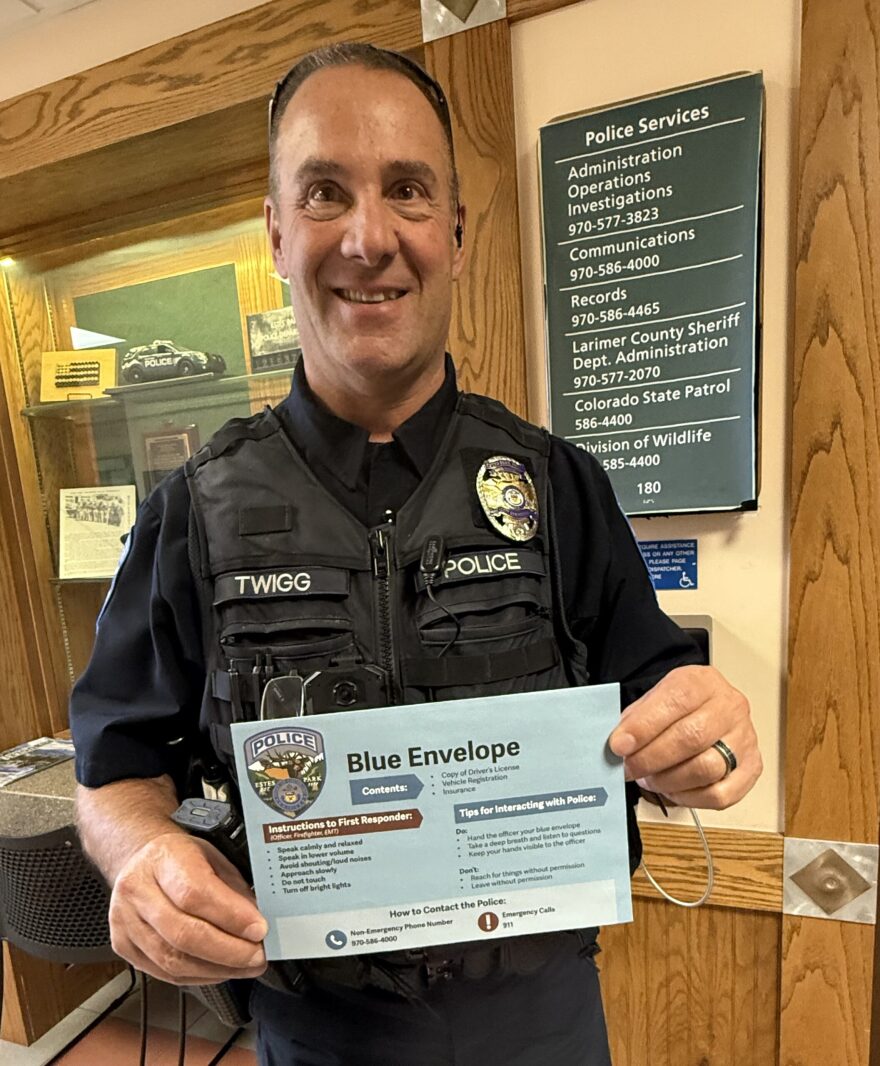 A person in a police uniform holds a large blue envelope.