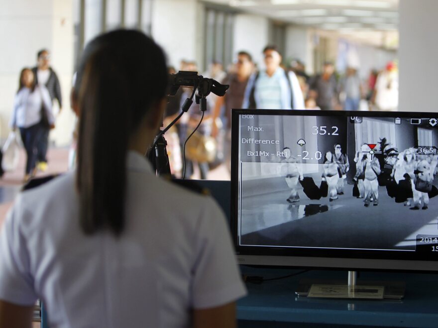 Airline passengers traveling from the United Arab Emirates pass through a scanner designed to detect people with a fever in Manila, the Philippines, in April.