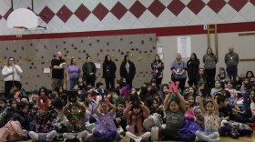 Students at Alaska Native Cultural Charter School hold up letters that read "quyana" during an assembly.