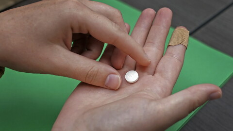 A patient prepares to take the first of two combination pills, mifepristone, for a medication abortion during a visit to a clinic in Kansas City, Kan., Oct. 12, 2022.
