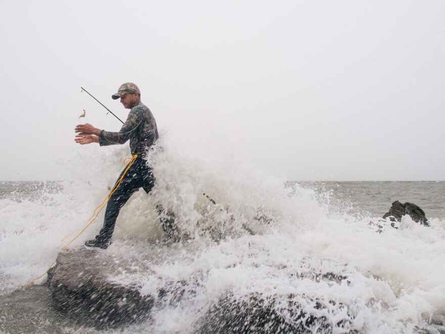 Celbing Diaz fishes ahead of Tropical Storm Nicholas in Galveston, Texas, on Monday. The storm grew overnight and made landfall as a hurricane early Tuesday.
