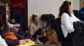 Steph Wise, Jackson Hole Community Housing Trust director of operations, sits on the floor near the door of the packed conference room in the basement of the “Old Teton County Library,” which is now office space.