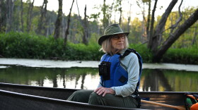 A woman wearing a life vest sits in a canoe on a river