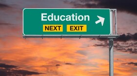 Education next exit freeway sign with sunset sky.