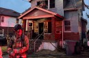 An unnamed firefighter stands before a burnt house.