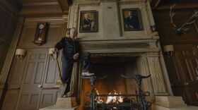 Tom Cruise poses with a shovel in front of a large fireplace.