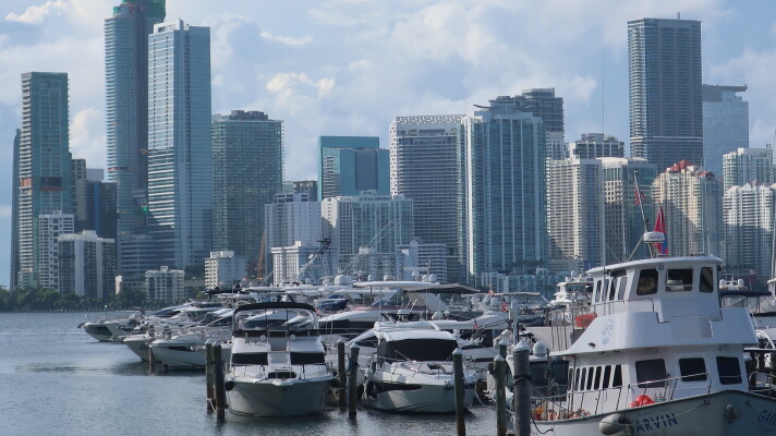 Many boats at a marina are in the foreground, and in the background, the Miami skyline.