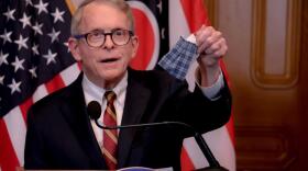 Gov. Mike DeWine holds a mask made by his wife Fran at a press conference in April.