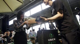 A delivery man brings ordered food during a press conference of UberEats, which opens in Tokyo on Thursday, on Wednesday, Sept. 28, 2016. (Eugene Hoshiko/AP)