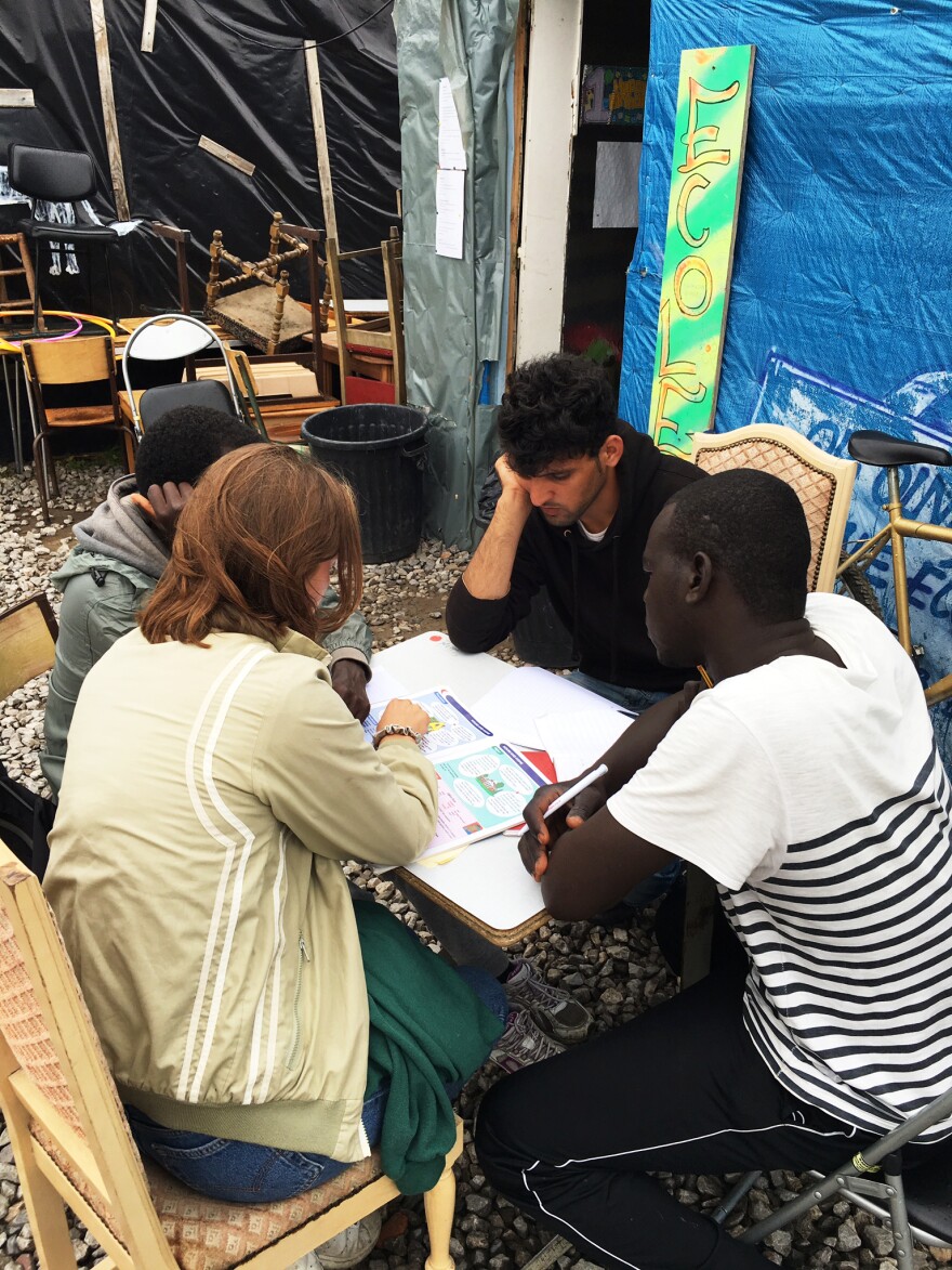 A volunteer at The Jungle gives migrants an English lesson there.