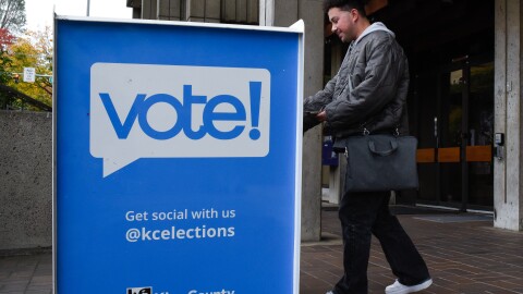 A person drops off a ballot in a ballot box. 