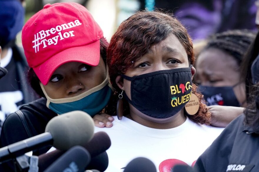 Two Black women stand at a news conference in Louisville. The woman on the right is the mother of Breonna Taylor, who was shot by Louisville police.