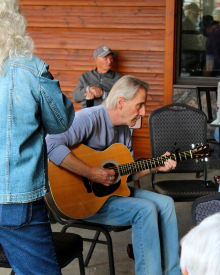 A man sits in his chair playing the guitar.