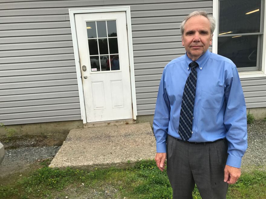 A man wearing a blue shirt and tie stands outside near a doorway