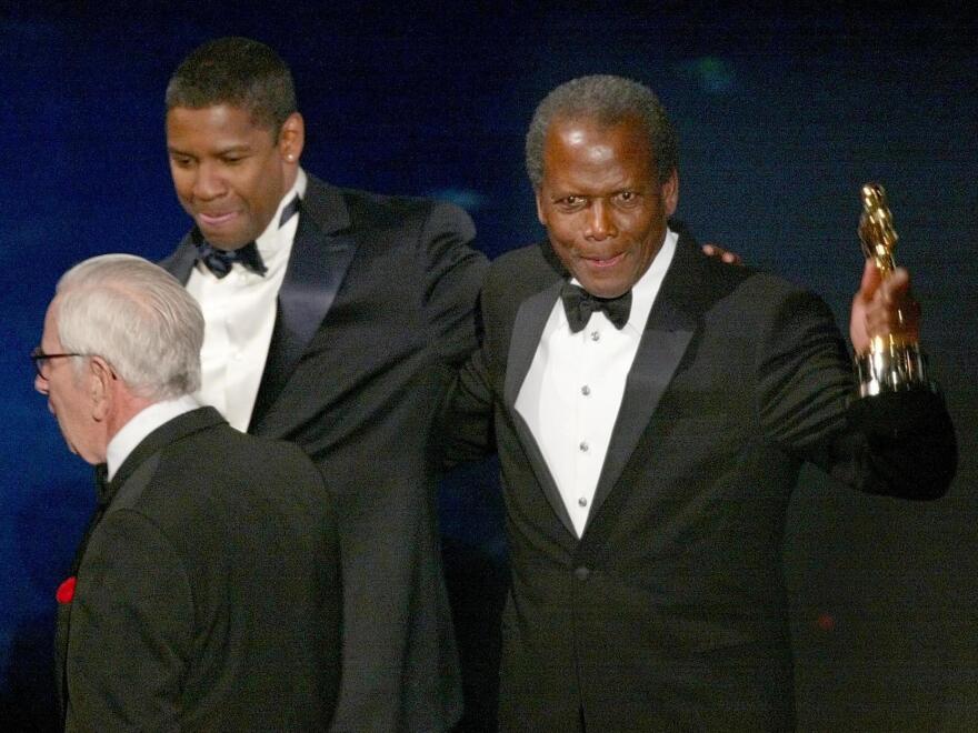 Sidney Poitier walks off the stage with presenter Denzel Washington after receiving an honorary Oscar during the 74th Academy Awards at the Kodak Theater in Hollywood, 24 March 2002.