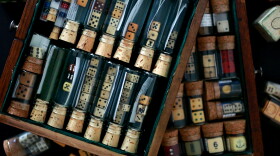 Dice and game pieces of various shapes and sizes collected in vials inside a box.