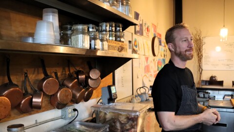 Chef Evan Hennessey in the kitchen of his restaurant Stages, two days after winning the James Beard Award for Best Chef in the Northeast. Copper pots hang behind him, trays of ingredients are lined up on a nearby counter, and handmade drawings line the walls.
