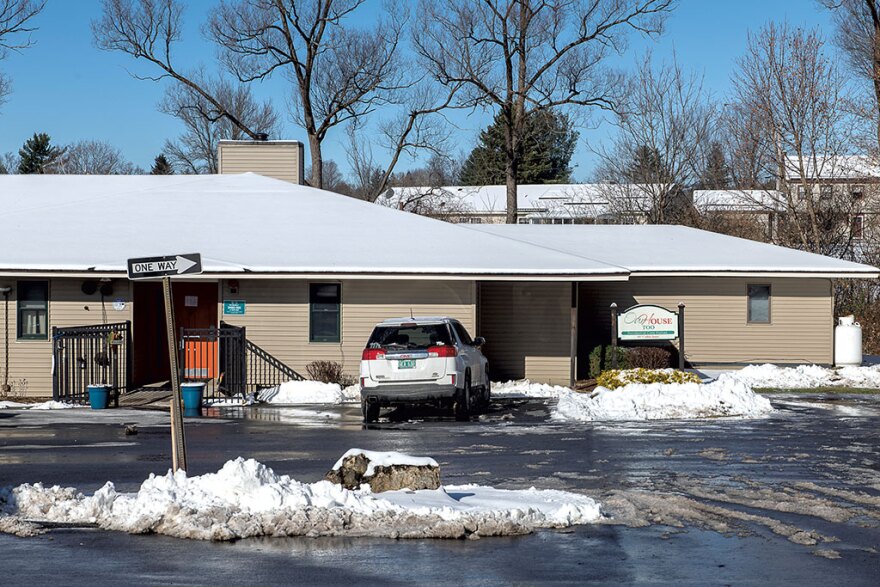 The front of Our House Too as seen from a snowy parking lot on a sunny day. It is a beige building with a sign out front.