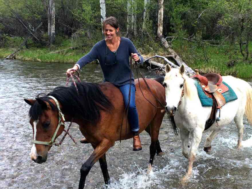 Author Alexandra Fuller on horseback crossing a river.